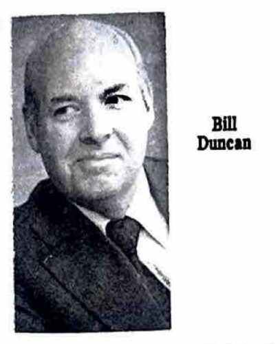 Portrait image of Bill Duncan. He is glancing to the left with a slight smile. He is wearing a dark suit jacket and black tie with a white shirt.